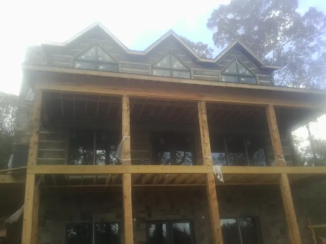 Dormers and porch framing on a large log home under construction — Roof Coating work by our crew in Hallieford