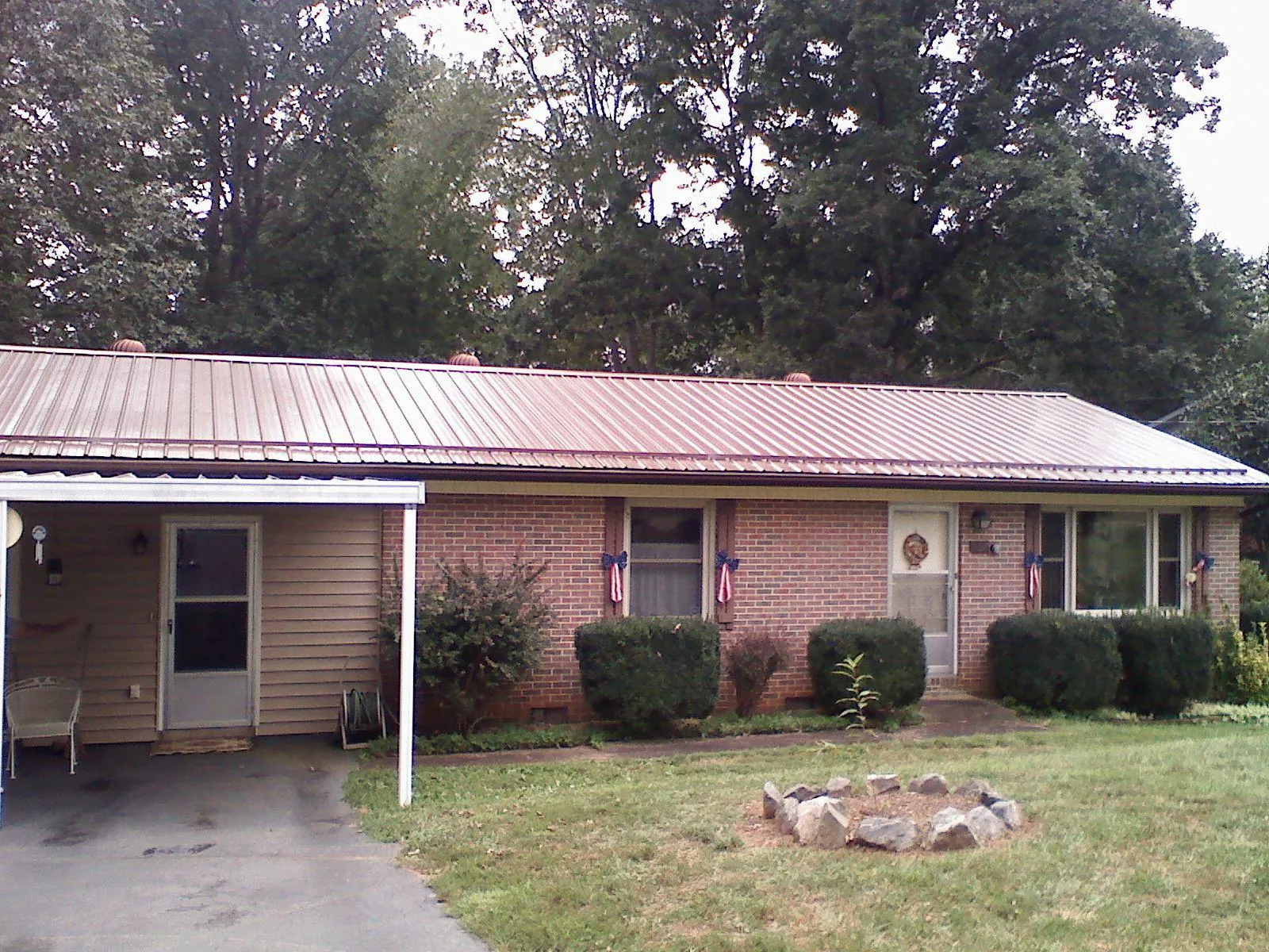 Bronze metal roof and carport on a brick ranch home — Roof Repair work by our crew in Hallieford