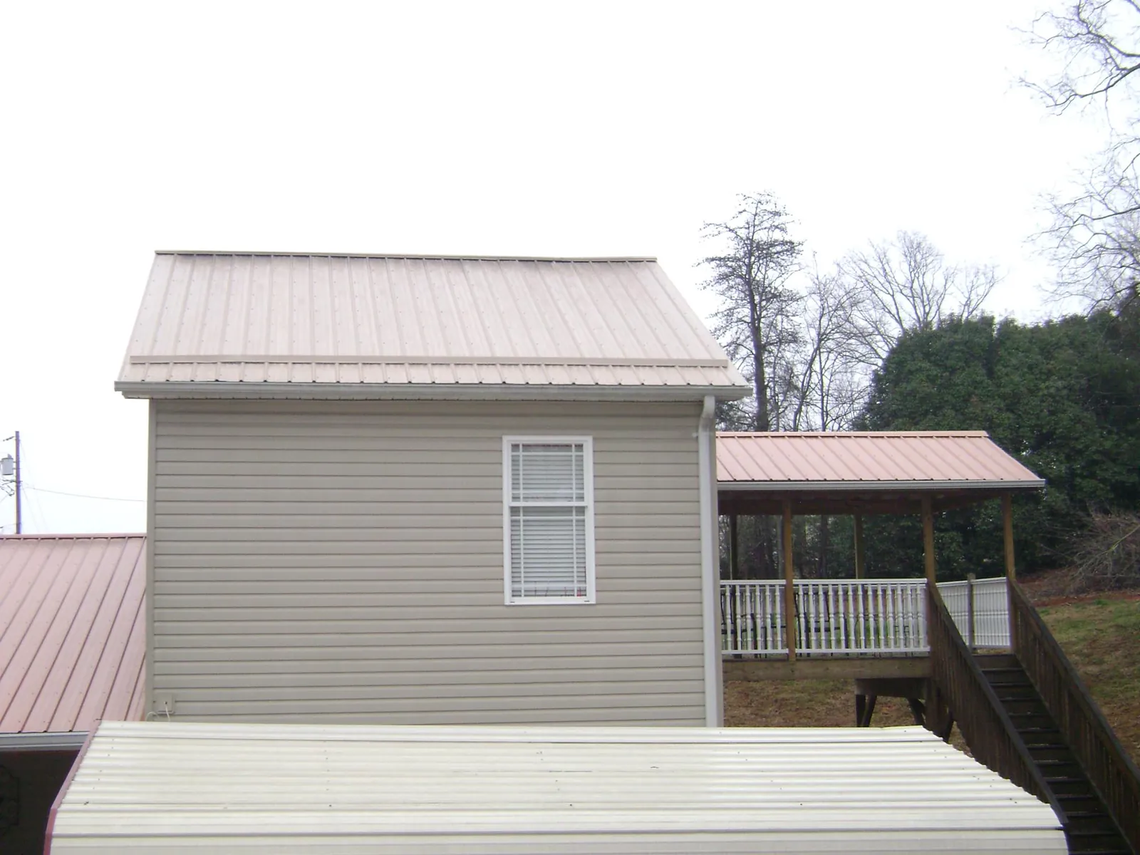 Tan metal roofs on a two story addition and attached porch, from a Roof Replacement job in Hallieford
