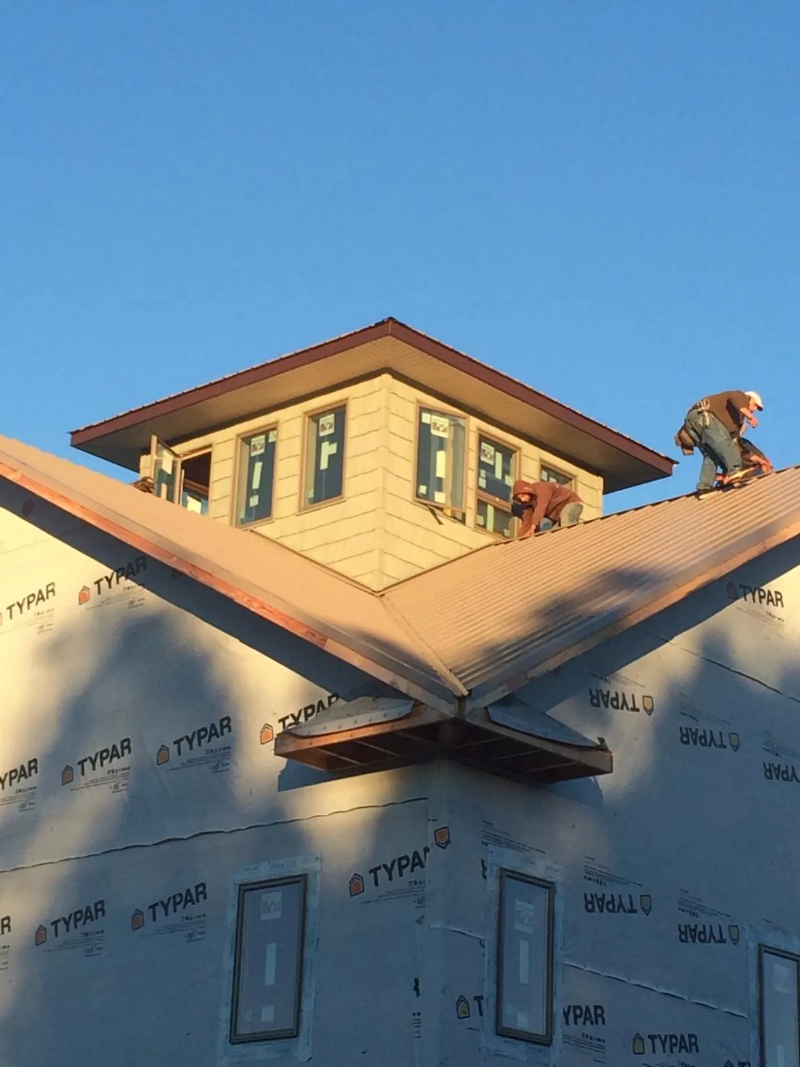 Roofers working around a rooftop cupola on a new metal roof at sunset — Roof Waterproofing in Hallieford by Roofing Brothers
